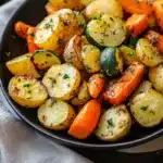 Garlic herb roasted potatoes carrots and zucchini on a rustic table